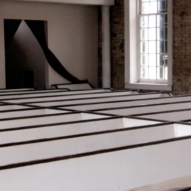 Church sanctuary with white pews and tall windows