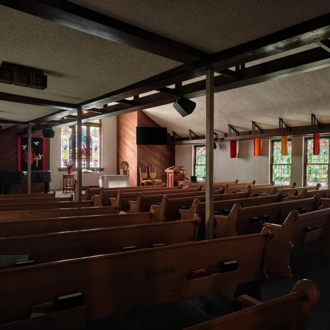 Church sanctuary with wooden pews and stained glass